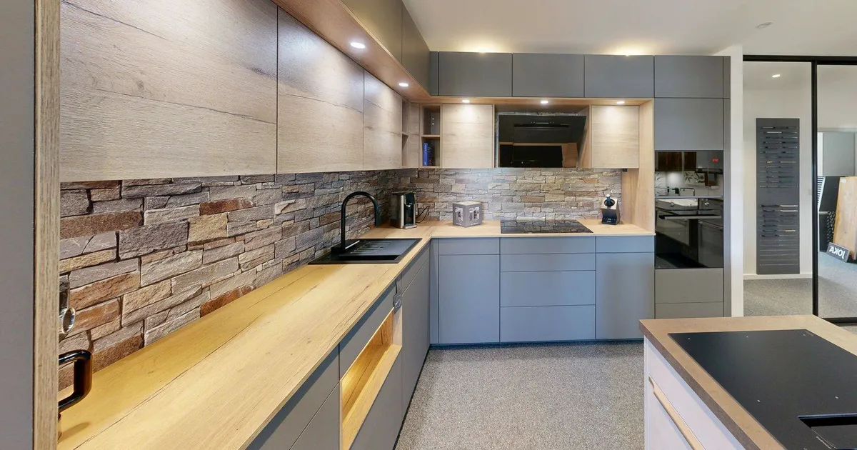 Küchenzeile mit Natursteinrückwand, Eichen-Arbeitsplatte und grauen grifflosen Fronten im Showroom von Küchen Scheck